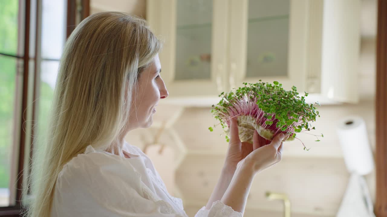Woman inspecting fresh radish sprouts in kitchen