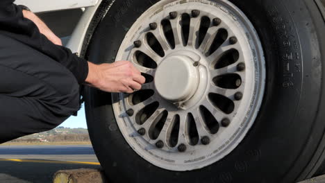 man checks tyre pressure of aircraft wheel close up