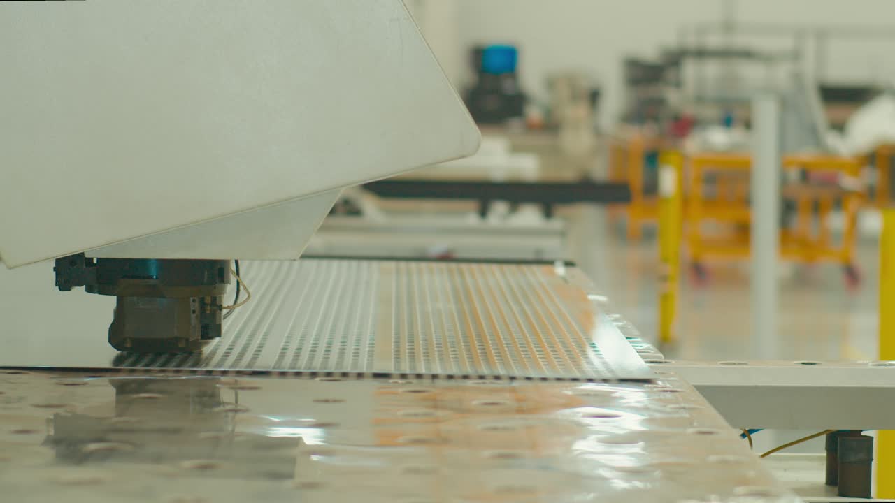 Metal drilling machine working on an aluminum sheet in a metal factory