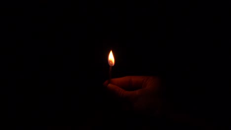 hand holding a match igniting with a big flame in slow motion