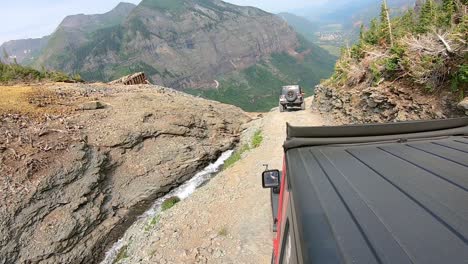 POV-from-rooftop-of-4WD-vehicle-following-another-on-Black-Bear-Pass-trail-along-Ingram-Creek-and-pass-abandoned-mine-building-near-Telluride-Colorado