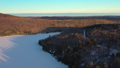 flying above a snowy forest towards a railroad trestle in northern maine at sunset