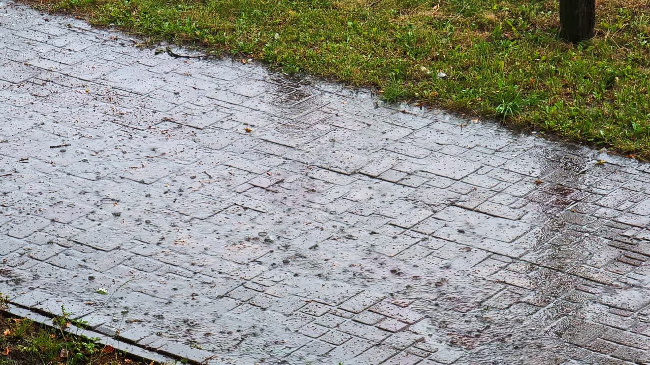 Rainfall hitting brick pavement as water splashes during summer shower