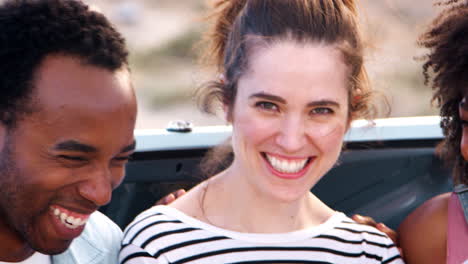 friends on a trip sitting in car trunk at roadside, close up