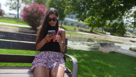 una adolescente usando un teléfono inteligente en el parque