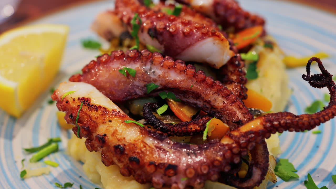 Close up of grilled octopus on a puree and a piece of lemon at a restaurant