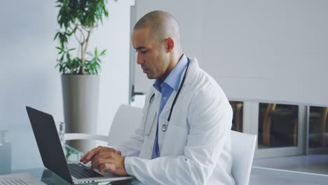 Male-doctor-using-laptop-at-desk-in-office-4k