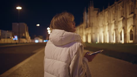 girl tourist photographing ancient cathedral on smartphone at night closeup.