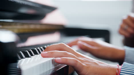 close up of pupil with teacher playing piano in music lesson