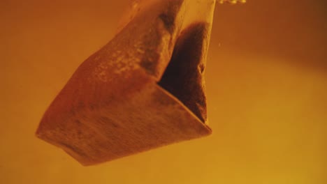 close up of tea bag diffusing in a clear glass. macro slow motion shot of the process of brewing herbal.