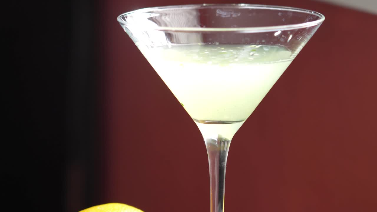 hermoso cóctel de bebida en copa de martini con limones, rodajas de pepino y ramita de menta al lado
