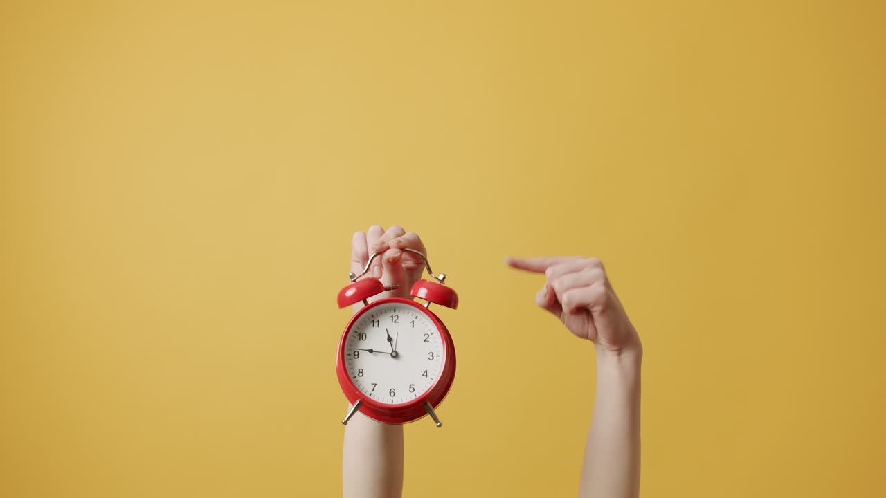 mujer gestando con sus manos con despertador rojo en fondo amarillo