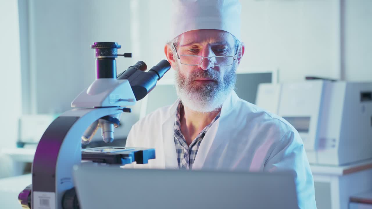 Focused Scientist Working with Microscope and Laptop in Laboratory