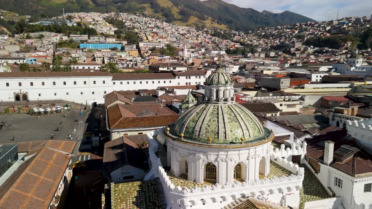 Orbita aerea con effetto parallasse intorno alle cupole a coste verdi e piastrellate della Iglesia Compañía de Jesús, rivelando Piazza San Francisco e il paesaggio urbano andino.
