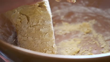 hand kneading and mixing gently floured ingredients in bowl to make dough, preparation for homemade baking cookies biscotti cantucci, close up view