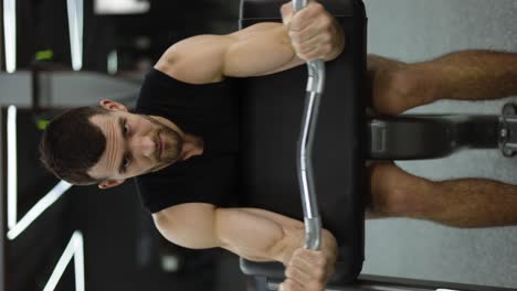 Muscular-bodybuilder-doing-weight-lifting-in-gym-on-chair