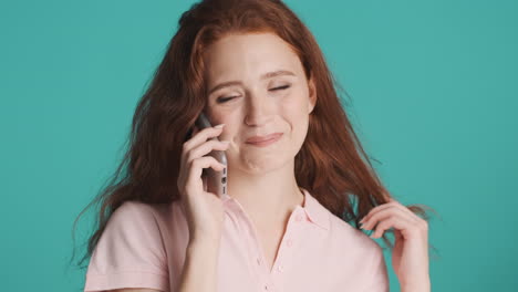 Redheaded-girl-in-front-of-camera-on-turquoise-background.