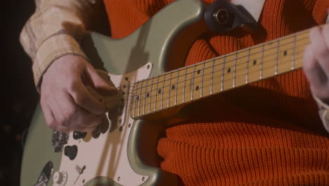 close up of male musician playing guitar and singing during live music perfomance