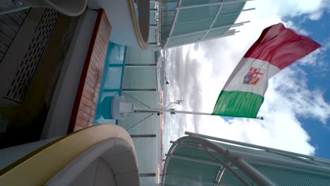 flag of italy waving at the stern of a sailing cruise ship
