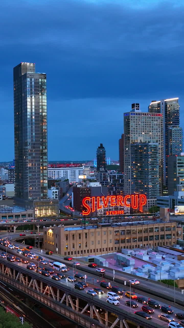 Long Island City, Queens, New York. Gorgeous modern buildings full of lights. Busy traffic around Silvercup Studios in the evening. Vertical video