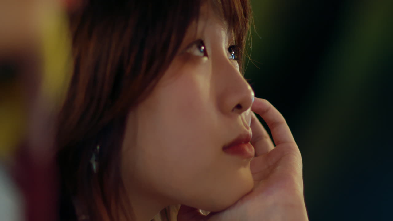 머리를 손에 고 밤에 주위를 둘러보는 소녀의 클로즈업