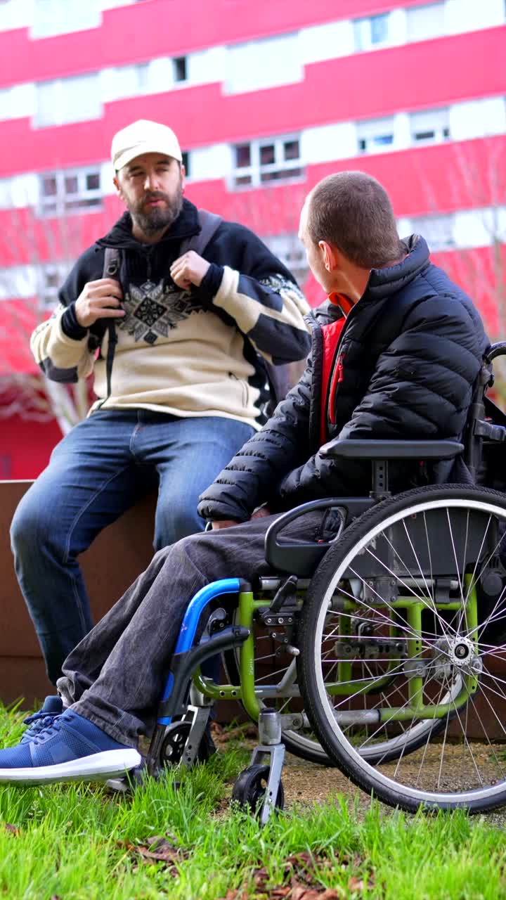 Two men, one in a wheelchair, spending time together outside a building