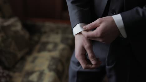 handsome groom fixes his cuffs on a jacket. wedding morning. businessman