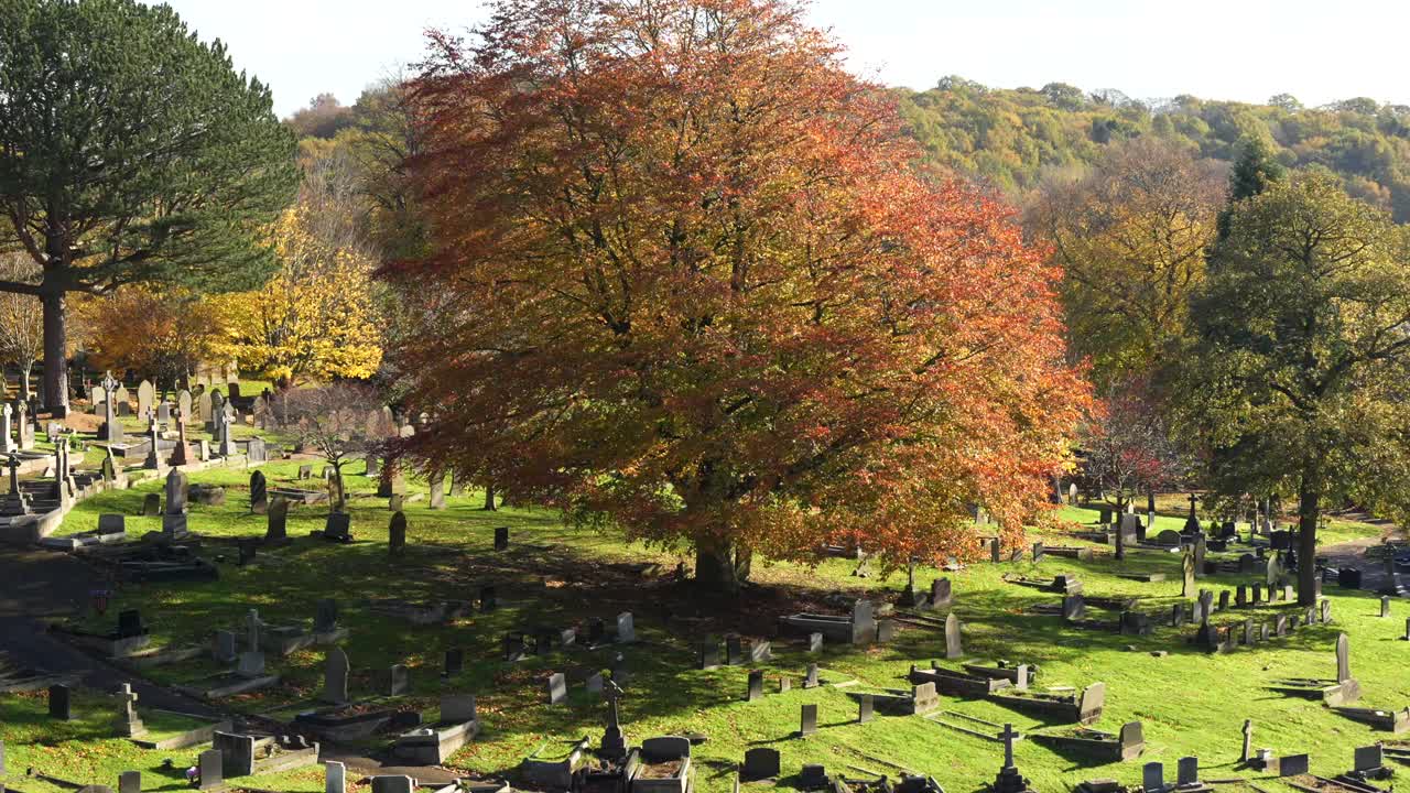 Peaceful graveyard in autumn with orange foliage and old headstones