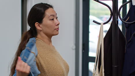 woman getting home from food shopping hanging up coat and carrying bag of fresh vegetables indoors into kitchen 2