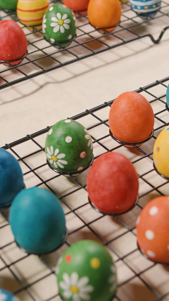 After coloring, camera pulling back shifting focus to reveal decorated eggs resting on racks to dry