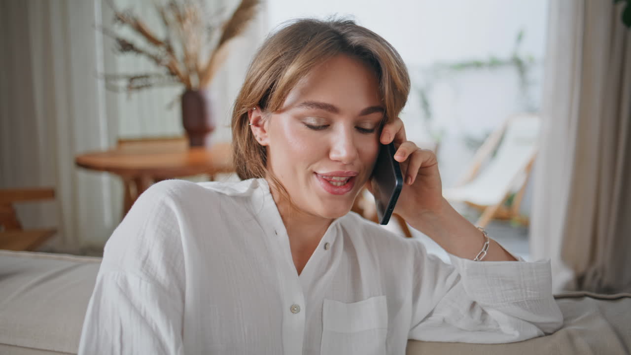 Joyful woman gossiping mobile phone conversation sitting cozy couch closeup