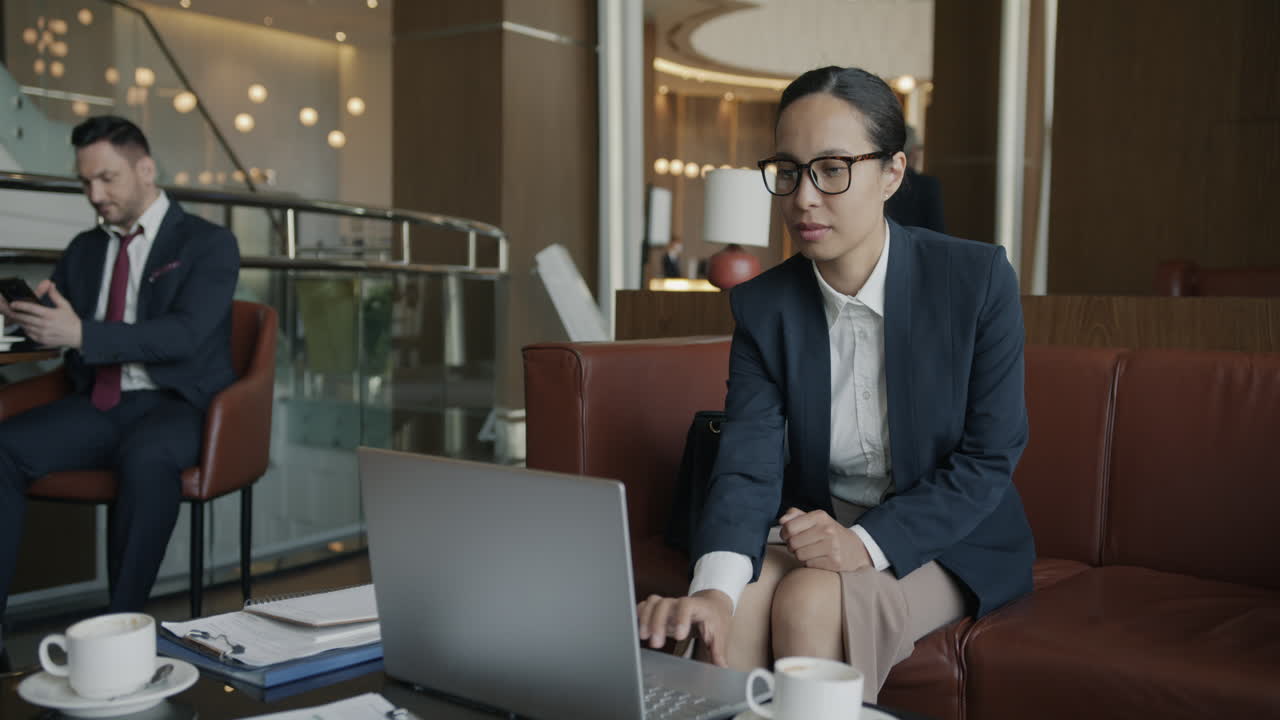 Businesswoman Working on Laptop in Hotel Lobby