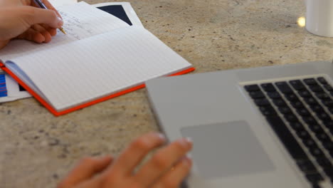 mujer usando un cuaderno y una computadora portátil