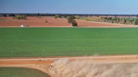 Von-Oben:-Ein-Traktor-Zieht-Eine-Planierraupe-über-Einen-Feldweg,-Auf-Dem-Viel-Staub-Aufsteigt