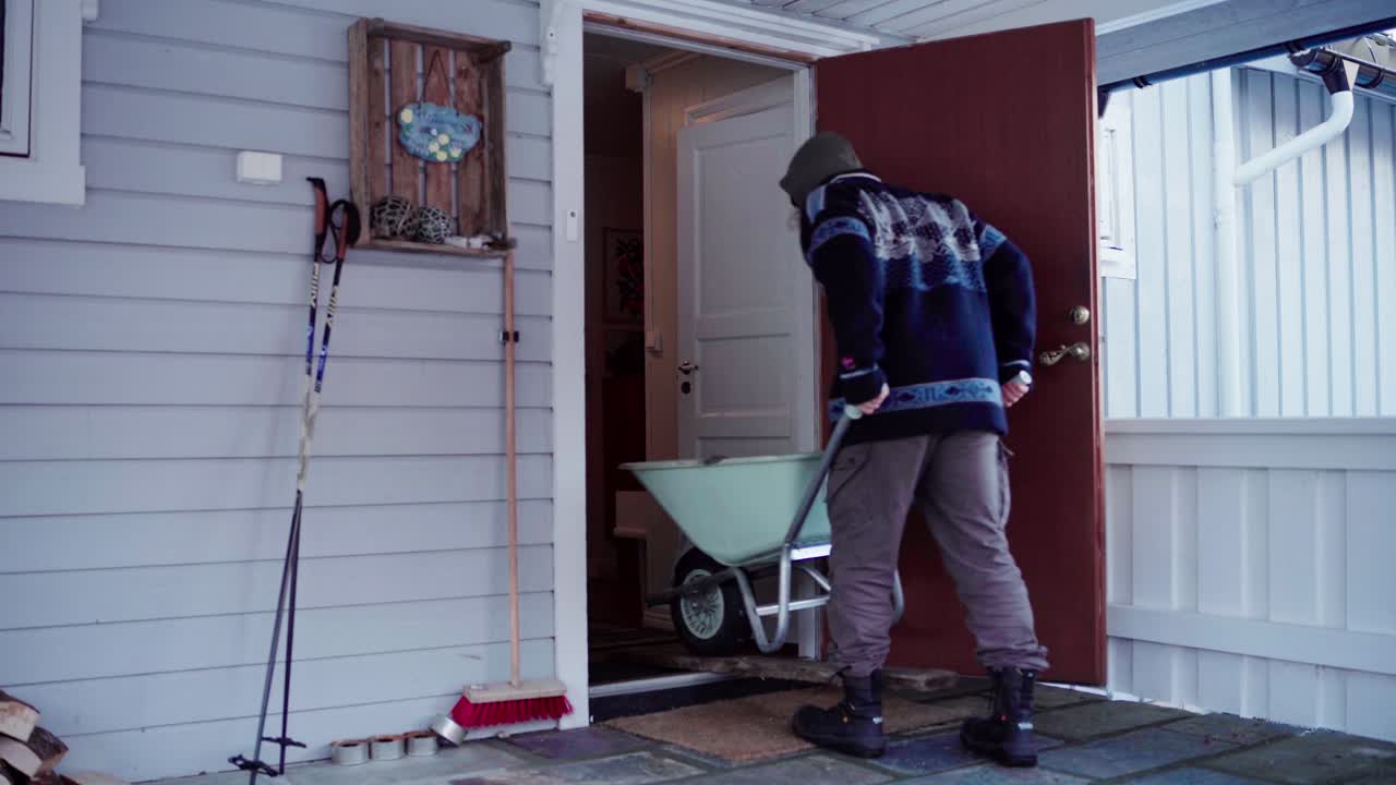 A Man Utilized a Plank of Lumber to Facilitate Bringing the Wheelbarrow Into the House While Carrying Materials for the DIY Hot Tub - Static Shot