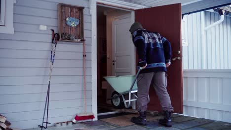 un hombre utilizó una tabla de madera para facilitar la introducción de la carretilla en la casa mientras llevaba materiales para la bañera de agua caliente diy - toma estática
