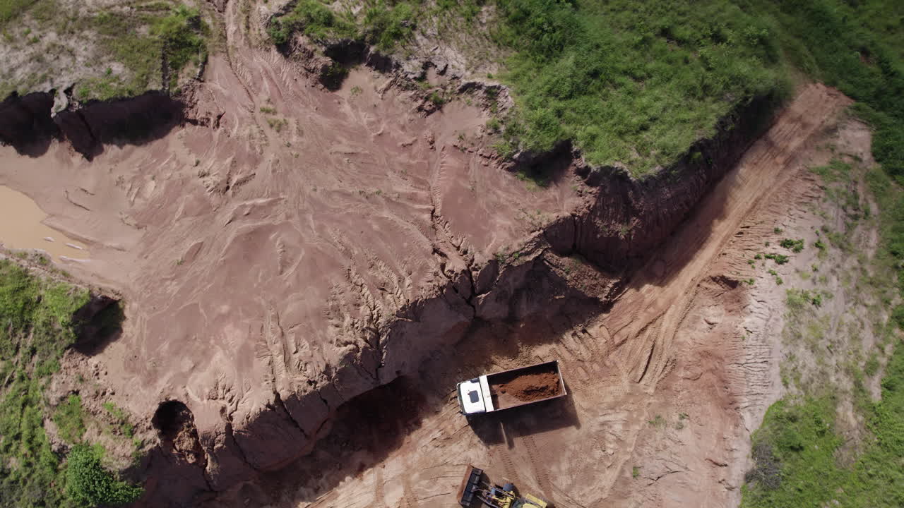 Ripresa con drone di un escavatore che carica su un camion in un cantiere edile.