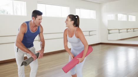 Feliz-Hombre-Caucásico-Y-Mujer-Instructora-De-Yoga-Dándose-La-Mano-Después-De-Practicar-En-El-Gimnasio,-Cámara-Lenta