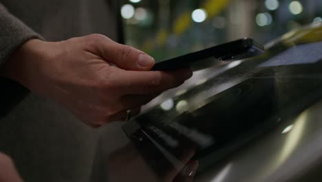 mujer usando un teléfono inteligente en un quiosco de pantalla táctil