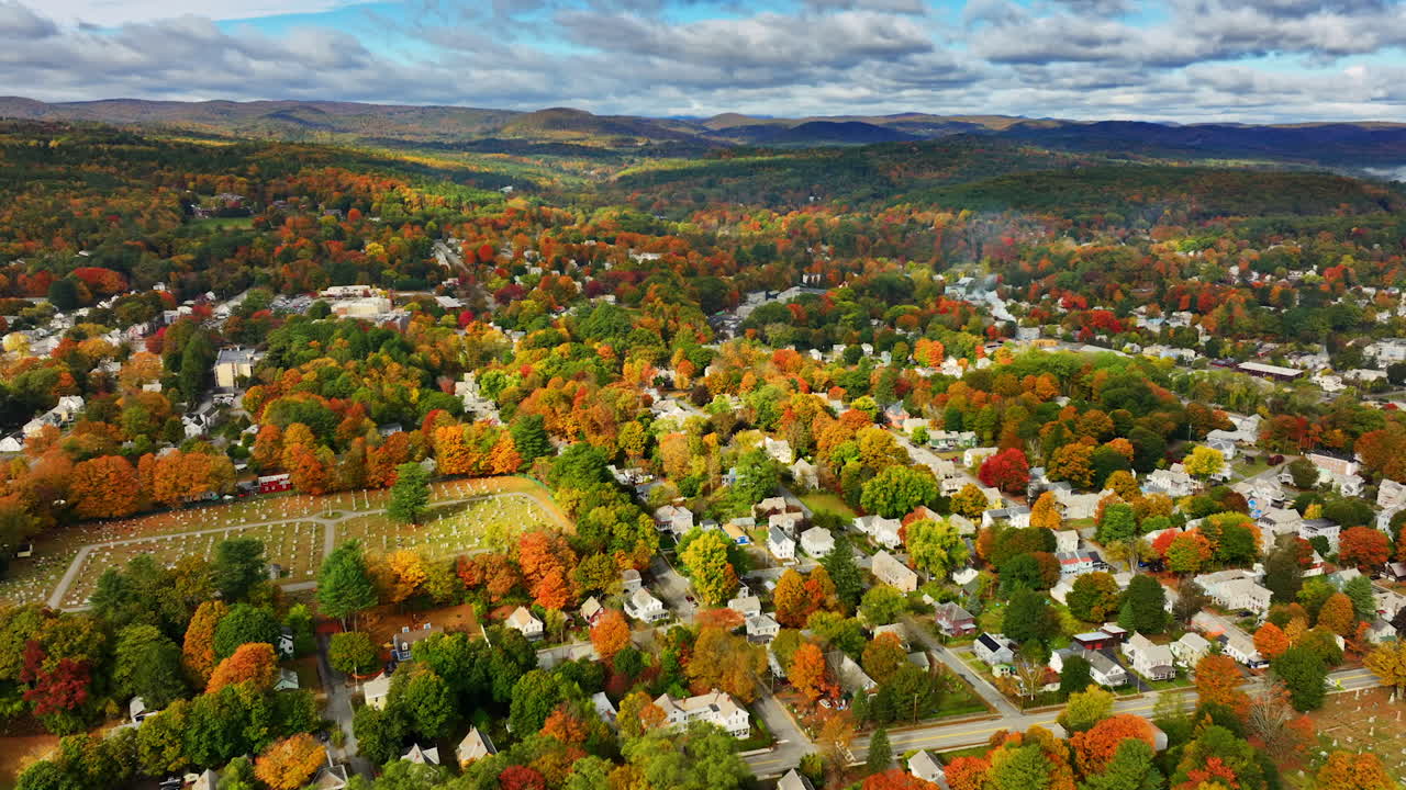 Vivid panorama of Vermont, New England, USA in warm autumn. Cottages and bright trees under the overcast sky. Aerial perspective.
