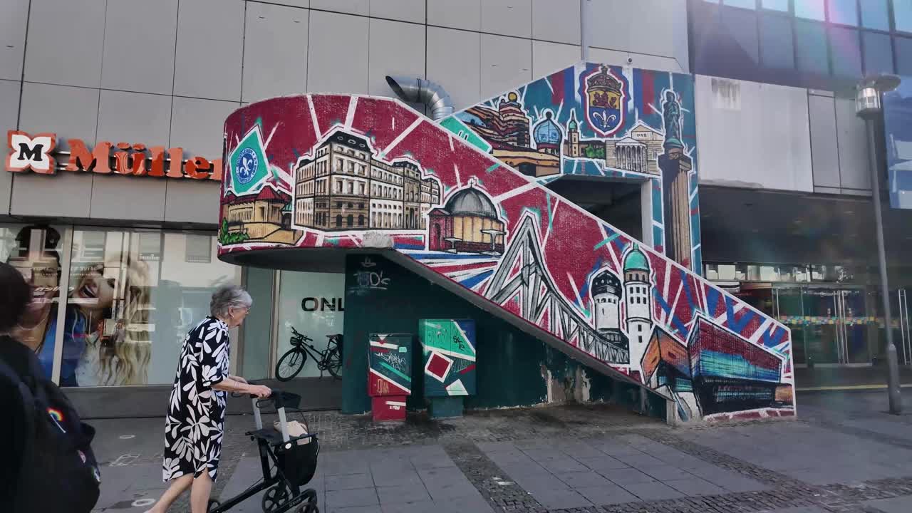 Art on building staircase and people passing, shopping centre in Darmstadt, Hessen, Germany