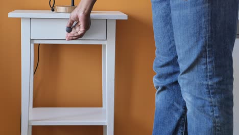 person opening a drawer of a white nightstand