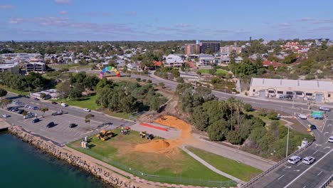 construction bulldozers dig dirt on swan river bank near fremantle's containbow sculpture, perth, western australia