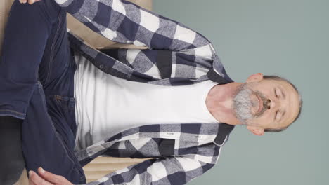 Vertical-video-of-Old-man-meditating-looking-at-camera.