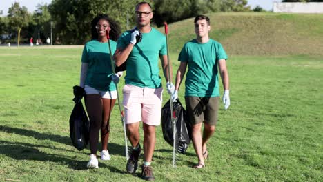 smiling volunteers with rakes and bags