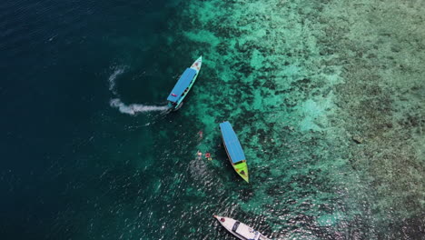 boat tour with tourists on the clear and clean water of beach in bali, indonesia