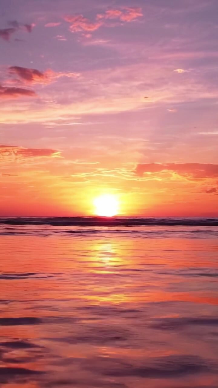 Stunning Sunset Over Calm Ocean Waters, with Vibrant Hues of Pink, Orange, and Purple Reflected on the Surface, Creating a Serene Evening Atmosphere