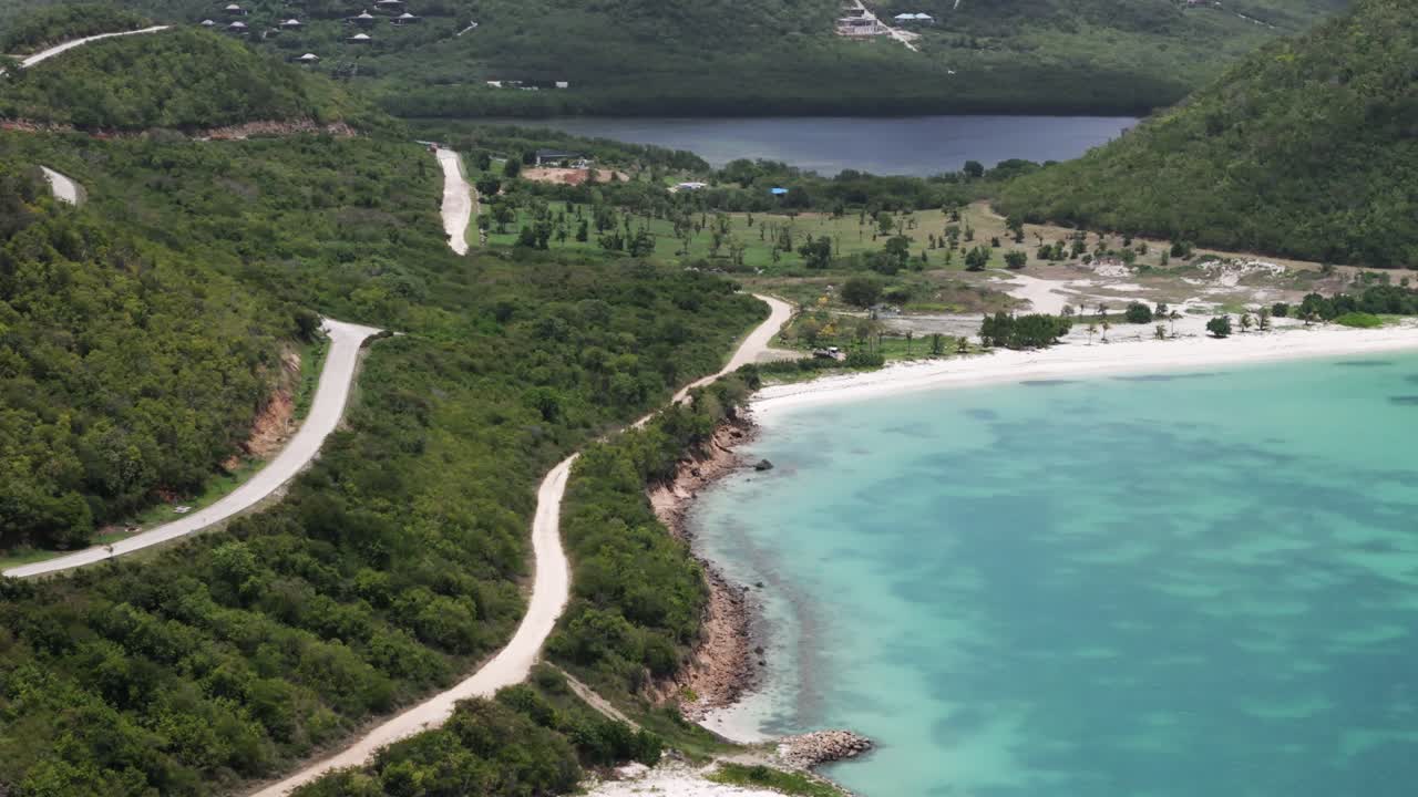 Aerial view of a beautiful tropical beach with turquoise water and a winding road