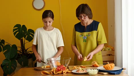 Mature-woman-teaching-granddaughter-to-chop-veggies