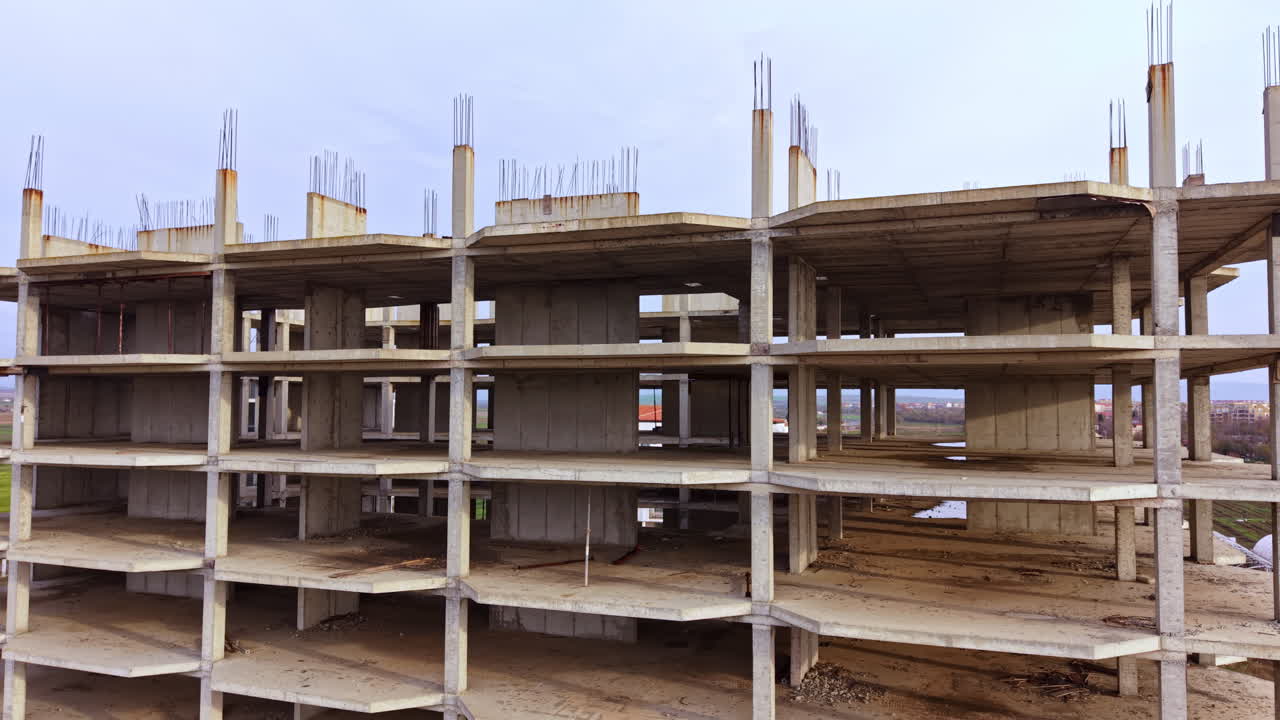 Construction of a modern building showcases its skeletal structure under a clear sky in a developing area, symbolizing progress and opportunity